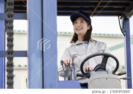 倉庫でフォークリフトを運転する若い女性 130095980