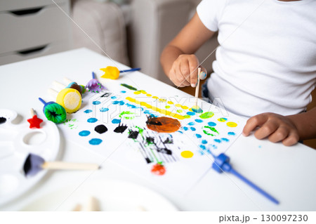 Child painting colorful abstract art with sponges using yellow, blue, green, and black dots Child painting colorful abstract art with sponges using yellow, blue, green, and black dots 130097230