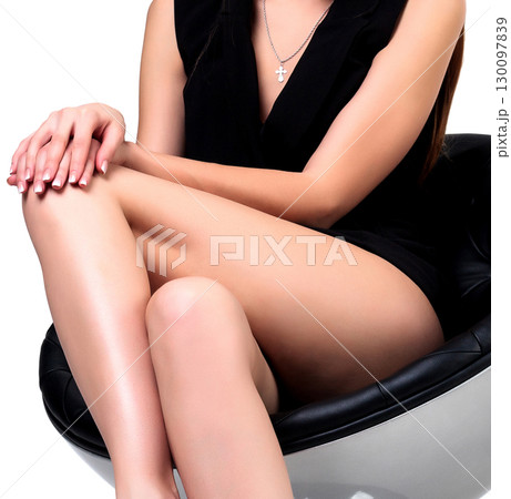 Woman with long legs sitting in a chair, isolated on white background 130097839