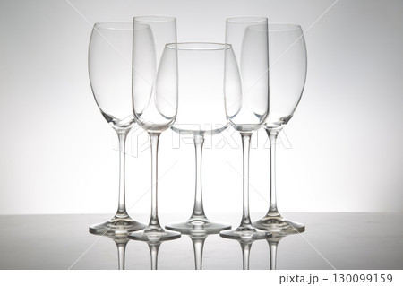A minimalist display of five empty wine glasses with slender stems 130099159