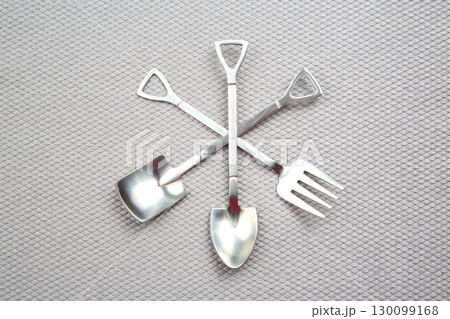 decorative fork and spoons in the form of spades on a gray background. food tools. decorative fork and spoons in the form of spades on a gray background. food tools. 130099168