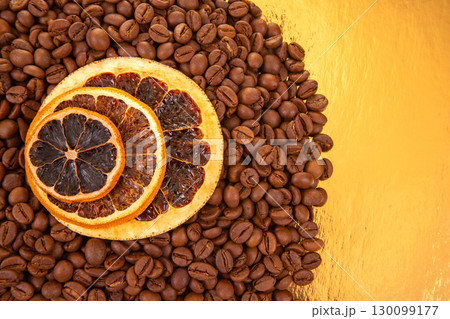 Warm coffee beans and dried orange slices on a reflective golden surface Warm coffee beans and dried orange slices on a reflective golden surface 130099177