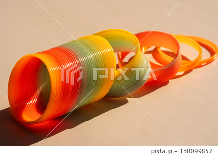 Rainbow spring toy and rings arranged diagonally on surface 130099857
