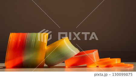 Rainbow spring toy and rings lying on surface with shadows Rainbow spring toy and rings lying on surface with shadows 130099875
