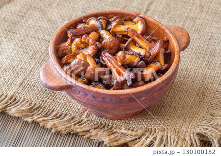 Rustic bowl filled with golden fried chanterelle mushrooms on table 130100182