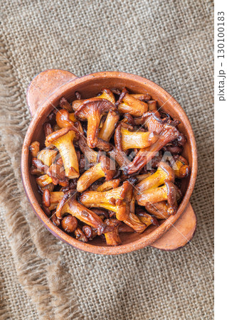 Rustic bowl filled with golden fried chanterelle mushrooms on table Rustic bowl filled with golden fried chanterelle mushrooms on table 130100183