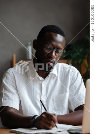 Student smiling while taking notes in a bright and modern study space 130100309
