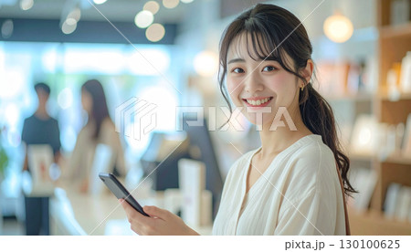 スマホを提示して支払いする自然な笑顔の女性の会計シーン 130100625
