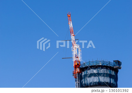 建設中の煙突と青空に伸びるクレーン 130101392