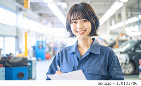 整備工場で書類記入をする若い女性整備士の笑顔 130101786
