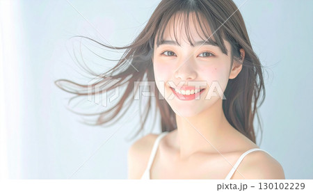 柔らかな風に髪が揺れるスタジオで微笑む若い女性 130102229