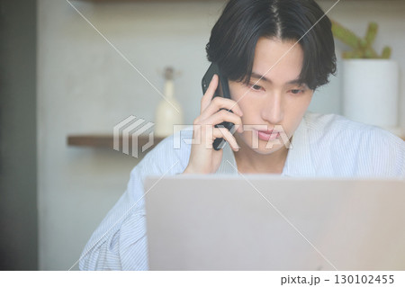 自宅で仕事をしているアジアの若い男性 自宅で仕事をしているアジアの若い男性 130102455