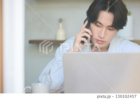 自宅で仕事をしているアジアの若い男性 130102457