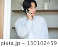 窓際で電話をしている若いアジアの男性 130102459