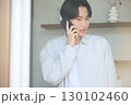 窓際で電話をしている若いアジアの男性 130102460
