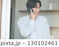 窓際で電話をしている若いアジアの男性 130102461