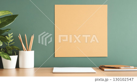 Workspace with blank yellow board, plant, and stationery items, creating calm and organized atmosphere for creativity and planning 130102547