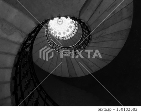 Black and white spiral staircase with ornate railing viewed from below 130102682