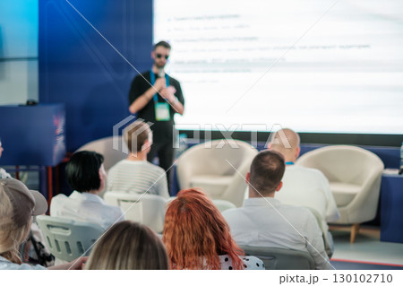 Speaker presenting to audience during conference with focus on attendees Speaker presenting to audience during conference with focus on attendees 130102710