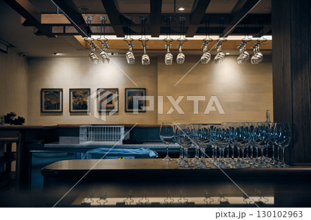 Modern bar interior with rows of hanging and standing wine glasses Modern bar interior with rows of hanging and standing wine glasses 130102963