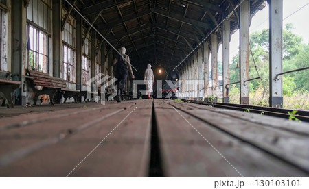 Haunted abandoned train station with ghostly figure walking alone, spooky eerie atmosphere for Halloween mystery and horror theme 130103101