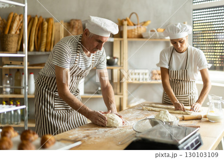 Elderly man and woman kneading and rolling out dough Elderly man and woman kneading and rolling out dough 130103109