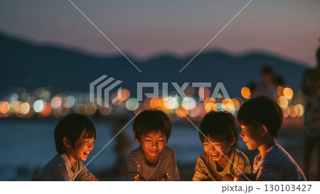 浜辺で手持ち花火を囲んで笑顔を見せる子どもたち 130103427