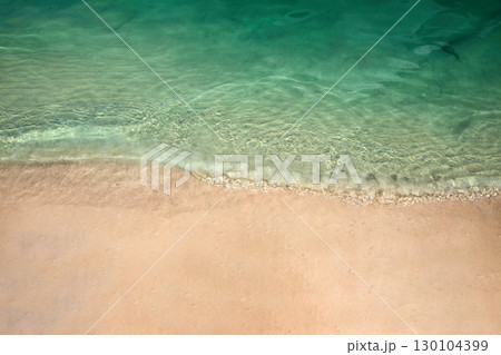 Serene Beach Shoreline. Clear turquoise water gently laps against a sandy beach. 130104399