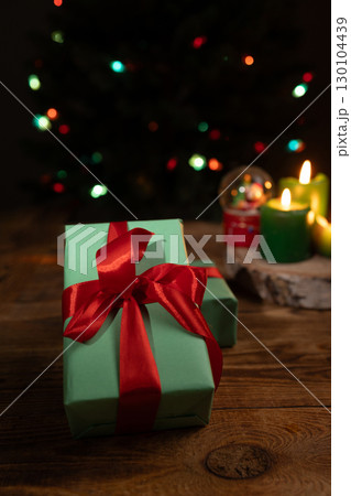 Wrapped Presents, Candles And Christmas Tree Lights On Wooden Surface 130104439