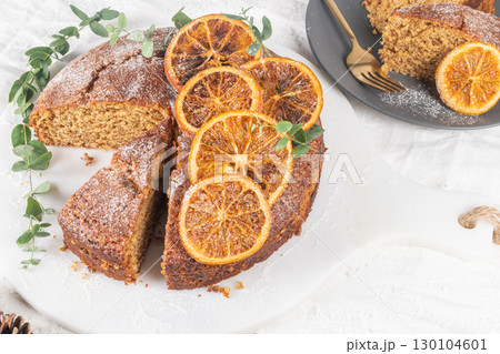 Christmas orange and spice cake. Decorated with dried oranges on kitchen countertop 130104601