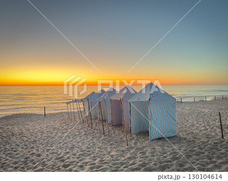 View of furadouro beach at sunset with blue and white striped beach tents. Ovar, Aveiro, Portugal 130104614