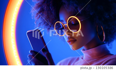 Portrait of a young stylish woman holding a smartphone in a vibrant futuristic neon lit setting Portrait of a young stylish woman holding a smartphone in a vibrant futuristic neon lit setting 130105386