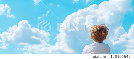 Serene image of a young boy standing in a natural setting gazing up at the picturesque sky filled with fluffy white clouds The child appears to be lost in thought Serene image of a young boy standing in a natural setting gazing up at the picturesque sky filled with fluffy white clouds The child appears to be lost in thought 130105645