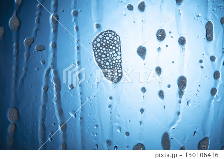 Water drops with foam on glass on a blue background. Water drops with foam on glass on a blue background. 130106416