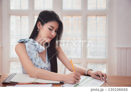 Asian woman holding pencil analysis the graph at the home office for setting challenging business goals And planning to achieve the new target. 130106688