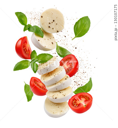 Floating slices of mozzarella cheese, cherry tomatoes and fresh basil with black pepper isolated on white background. Caprese salad ingredients concept. 130107175