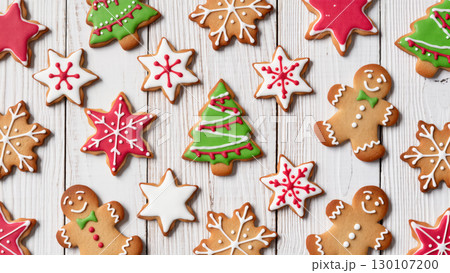 Christmas gingerbread cookies shaped like stars, trees, and people on white wooden background, decorated with colorful icing Christmas gingerbread cookies shaped like stars, trees, and people on white wooden background, decorated with colorful icing 130107200