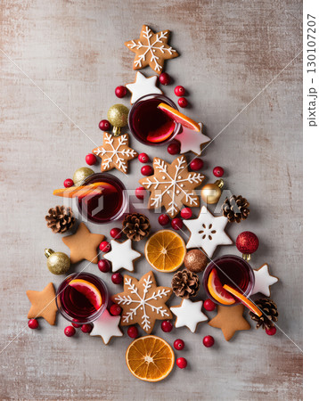 Christmas cookies, drinks, oranges and ornaments arranged in tree shape on rustic background, festive flat lay composition Christmas cookies, drinks, oranges and ornaments arranged in tree shape on rustic background, festive flat lay composition 130107207
