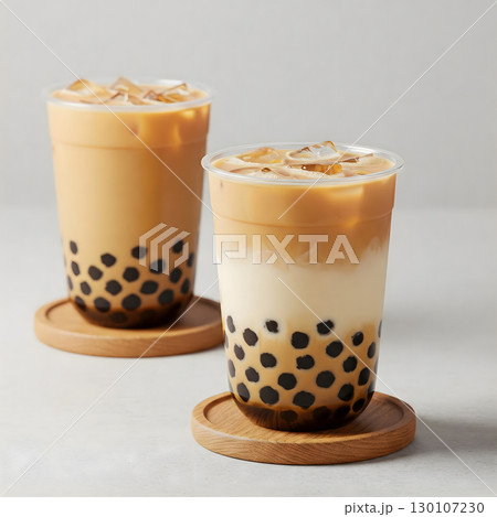 Two refreshing glasses of a popular Taiwanese beverage, with tapioca pearls settled at the bottom, stand on wooden coasters. Generative AI. 130107230