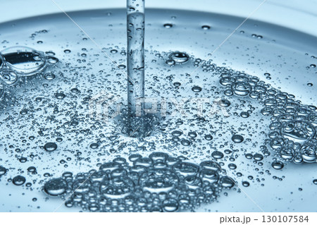 Shampoo or shower gel is poured from above and shows a bubbly texture. 130107584