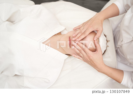 Caucasian female enjoying relaxing spa facial massage at wellness center Caucasian female enjoying relaxing spa facial massage at wellness center 130107849