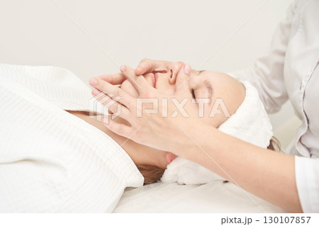 Relaxing facial treatment for young caucasian female in spa setting promoting 130107857