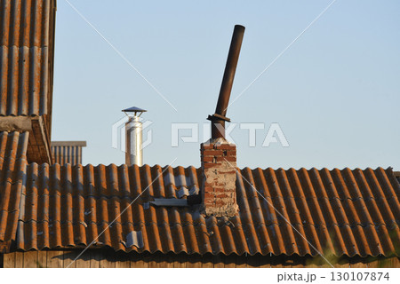 The chimney on the old house. An iron pipe and a slate roof. 130107874