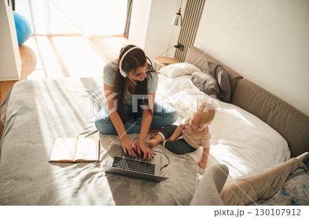 Showing laptop. Mother with her little son is at home in domestic room Showing laptop. Mother with her little son is at home in domestic room 130107912