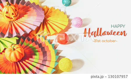Halloween holiday gift card with colorful paper fans, decorative pumpkin, lightening and jack o'lantern on a white background with congratulation inscription. Halloween background. Soft focus Halloween holiday gift card with colorful paper fans, decorative pumpkin, lightening and jack o'lantern on a white background with congratulation inscription. Halloween background. Soft focus 130107957