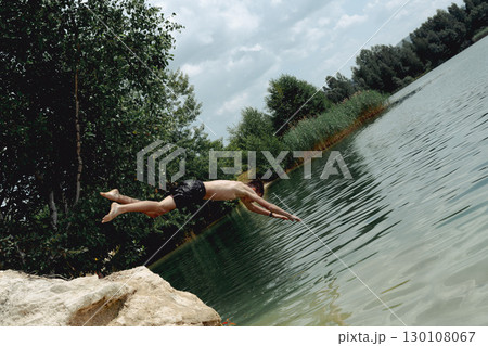 A young boy dives headfirst into the water on a summer day at the lake. Poland, Krzeszowek. A young boy dives headfirst into the water on a summer day at the lake. Poland, Krzeszowek. 130108067