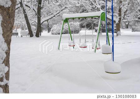 Snow-Covered Playground Swings in Winter Urban Park 130108083