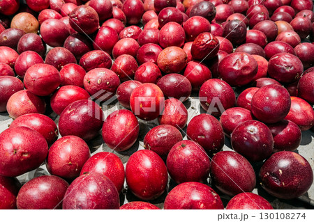 A large quantity of ripe purple passion fruits displayed on a market surface. Exotic fruits, tropical nutrition, farm-to-table, sustainable produce 130108274