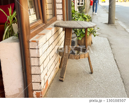 Weathered wooden table placed by the wall of a street cafe. Rustic charm, nostalgia and everyday urban simplicity. 130108507