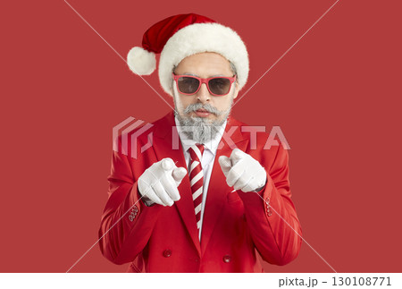 Santa Claus in stylish clothing and hat, looking through sunglasses and pointing directly at you Santa Claus in stylish clothing and hat, looking through sunglasses and pointing directly at you 130108771